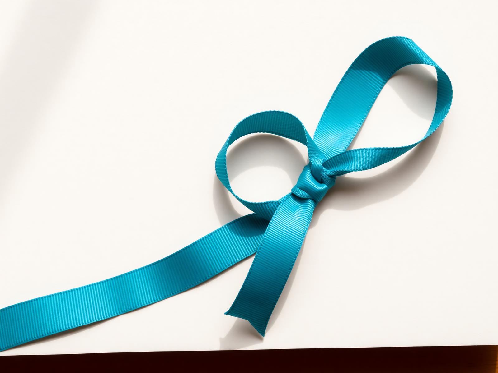 A teal grosgrain ribbon — Bondi blue — on warm paper